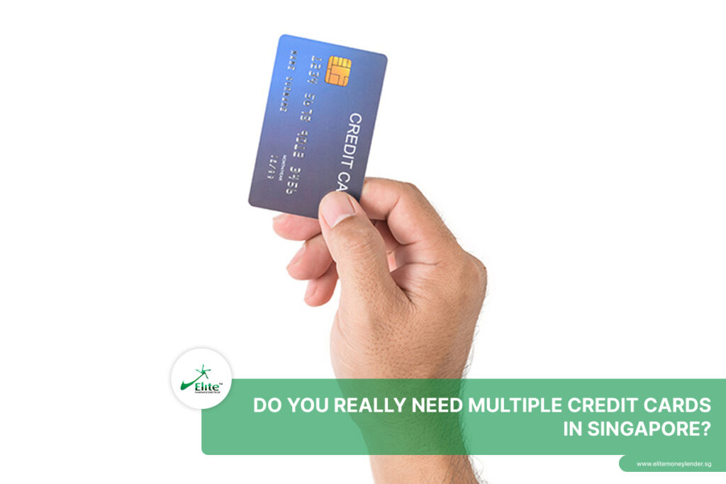A hand holding up a single blue credit card against